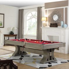 a pool table in the middle of a living room with a fireplace and large windows