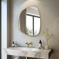 a bathroom with marble counter top and gold faucet, round mirror above the sink