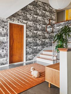 a dog is sitting on the floor in front of a wallpapered entryway