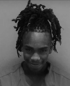 a black and white photo of a woman with dreadlocks on her head smiling