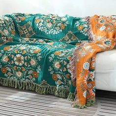 a white couch with a green and orange blanket sitting on it's back end