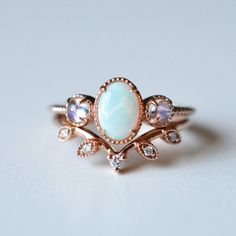 an opal and diamond ring on a white surface