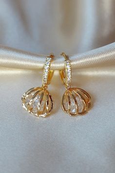 "Seashell-shaped earrings with simulated diamond applications in cubic zirconia and 24 karat yellow gold plated over stainless steel. These beautiful earrings have a unique design that combines perfectly with sunny summer days, they are also made with high quality materials that make them resistant to water and to use at the beach or pool. DETAILS ✨ Choker Material: Czech pearls beads. ✨ Choker Length: 34 cm + 7.5 cm / 13.3 inch +2.9 inch (Adjustable fit). ✨ Choker Width: 0.9 cm / 0.3 inch. ✨ Pe White Cubic Zirconia Pierced Hoop Earrings, Hoop Crystal Earrings With Cubic Zirconia For Pierced Ears, Cubic Zirconia Dangle Hoop Earrings, Ear Huggies, Ocean Treasures, Dainty Hoop Earrings, Seashell Earrings, Earrings Ear, Jewelry Cleaner