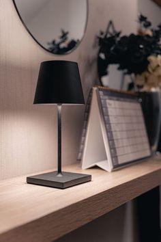 a table with a lamp, binder and mirror on it next to a plant