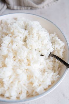 white rice in a bowl with a black spoon