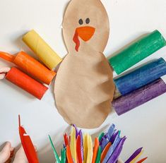 a paper turkey with carrots and crayons on the table next to it