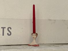 a red candle sitting next to a white wall