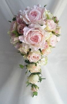 a bridal bouquet with pink roses and greenery on the bottom is laying against a white background