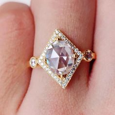 a woman's hand holding a ring with a large brown and white diamond in it