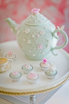 a tea pot and cupcakes on a tray