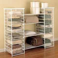 a white shelving unit with baskets and clothes