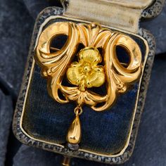 This storied brooch has a central yellow gold pansy flower within swoops and curves of ornate gold, and has a simple teardrop dangle at the bottom. Stamps on the brooch indicate the piece is Swedish, made in 1963 in Göteborg. The piece is crafted in 18k yellow gold and is finished with a pin stem and locking closure. Luxury Yellow Gold Brooches With Diamond Accents, Luxury Designer Yellow Gold Brooches, Luxury Yellow Gold Enamel Brooches, Luxury Yellow Gold Brooches For Gift, Antique Engagement Rings Sapphire, Estate Jewelry Rings, Wedding Ring Diamond Band, Pansy Flower, Pansies Flowers