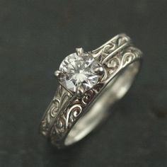 a white gold ring with a diamond in the center and filigrees around it