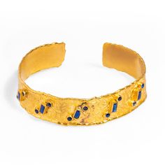 The Geometric Sapphires & Gold Design Cuff Bracelet is an elegant and bold accessory, featuring a 24k gold-plated thick cuff adorned with sapphire stones arranged in circular and rectangular patterns. These sapphire accents add vibrant color and energy, making the bracelet a unique statement piece.  Its versatile design effortlessly complements any style, ensuring it becomes a go-to accessory for elevating your look on any occasion. Details; Crafted with high-quality brass and plated with 24k gold for a luxurious finish. Sapphire stones Adjustable size Handmade in USA Sapphire Stones, Bold Accessories, Zodiac Jewelry, Sapphire Stone, Blue Bracelet, Fashion Jewelry Necklaces, Gemstone Healing, Polish Jewelry, Gold Design