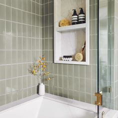 a white bath tub sitting under a bathroom mirror next to a shelf filled with vases