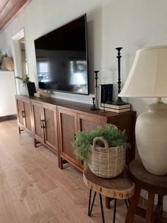 a large flat screen tv sitting on top of a wooden entertainment center next to a lamp