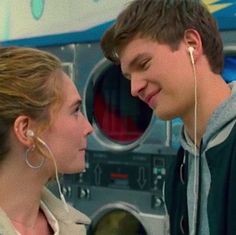 a young man and woman standing next to each other in front of a washing machine