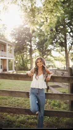 a beautiful young woman leaning on a fence