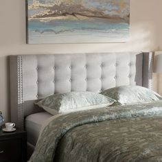 a bedroom with a bed, night stand and painting on the wall above it's headboard