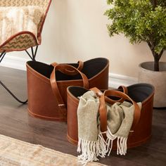 three brown buckets with blankets on the floor next to a chair and potted plant