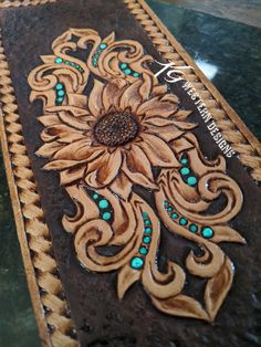 an intricately decorated piece of leather with turquoise beads and flowers on the inside is sitting on a table