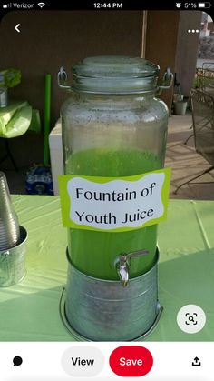 a green liquid in a glass jar with a sign on it that says fountain of youth juice