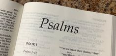 an open book with the word psalms written in black ink on it, sitting on a marble surface