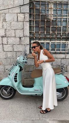 a woman standing next to a scooter on the street