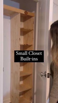 a woman standing in front of a closet filled with wooden shelving unit shelves next to a door