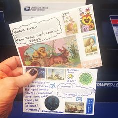 someone is holding up some mail with stamps on it and there are other postcards in front of them