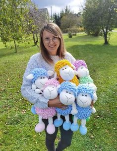 a woman is holding several stuffed animals in her arms and smiling at the camera while standing on some grass