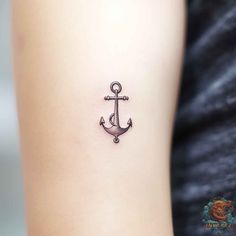 an anchor tattoo on the back of a woman's left arm is shown in black ink