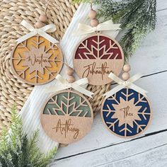 four wooden ornaments with the names of three different families on them and tied to ribbons