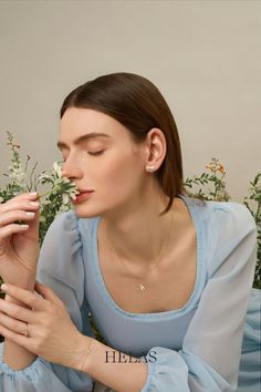 a woman sitting on the ground with flowers in her hand and wearing a blue dress