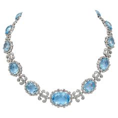 The Modern Blue Topaz Diamond 18K White Gold Necklace is a stunning piece of jewelry designed to add elegance and sophistication to any outfit. The necklace is crafted from 18K white gold, which gives it a lustrous and polished finish. The weight of the necklace is 69.39 grams, which gives it a substantial feel and a sense of luxury. The necklace features a graduated series of oval-shaped rose-cut blue topazes, which are the centerpiece of the design. Each topaz is surrounded by a scalloped border of circular-cut diamonds, which add a sparkling and glamorous touch to the necklace. The diamonds are of high quality, and they are carefully arranged to create a beautiful and balanced design. The blue topazes are spaced by circular-cut diamond links of similar design, which add a sense of conti Light Blue Diamond Necklace, High Jewelry Design, Blue Diamond Necklace, Necklace Royal, Balanced Design, Graduation Jewelry, Scalloped Border, Graduation Necklace, White Gold Necklace