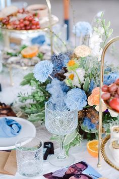 a table topped with plates and bowls filled with food next to vases full of flowers