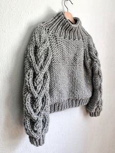 a gray sweater hanging on a white wall