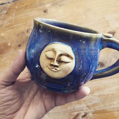 a hand holding a ceramic mug with a face on it's side and eyes closed