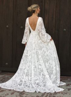 the back of a woman in a white wedding dress with long sleeves and open shoulders