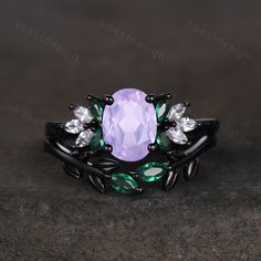 a ring with an oval shaped pink stone surrounded by green and white leaves on top