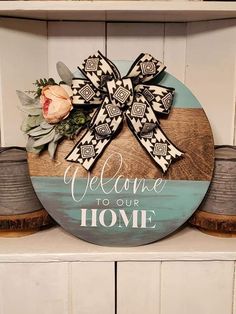 a wooden sign that says welcome to our home with a large bow and flowers on it