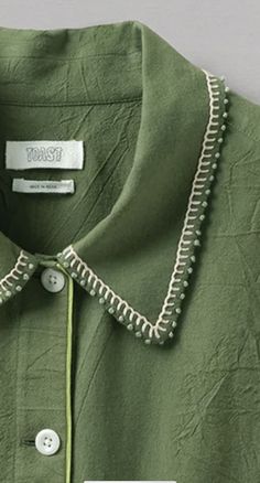 a green shirt with white trim and buttons