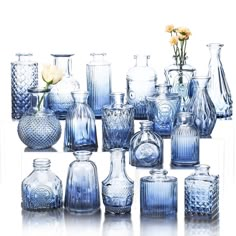 a collection of blue glass vases with flowers in them