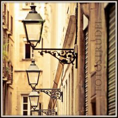 an old fashioned street lamp hanging from the side of a building in paris, france