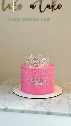 a pink cake sitting on top of a white counter next to a sign that says bake a cake