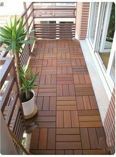 a small balcony with a potted plant on the floor and wooden slats around it