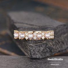 a close up of a ring with pearls and diamonds on it's side, sitting on a rock