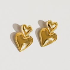 These layered hear earrings make heart earrings modern. This pairing of gold drop earrings features a simple stud connected to an elegant gold heart drop. We love this style for date night, girls' night, or really any night, as a matter of fact. 18k gold plated stainless steel Measurement (L x W inch): 1.2 x 0.8 Post back closure Tarnish free Trendy Gold Double Heart Earrings, Yellow Gold Heart Earrings For Valentine's Day Party, Trendy Heart-shaped Drop Earrings For Anniversary, Trendy Heart Drop Earrings For Anniversary, Gold Double Heart Earrings For Mother's Day, Trendy Anniversary Heart Drop Earrings, Modern Earrings For Valentine's Day Anniversary, Minimalist Gold Heart Drop Earrings, Trendy Gold Heart Earrings For Party