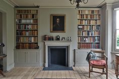 a living room filled with furniture and bookshelves next to a fire place in front of a window