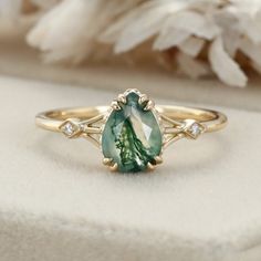 a green and white stone ring sitting on top of a table next to some flowers